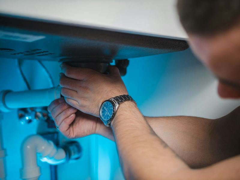 Lavabo altında sifon ve su tesisatı tamiri yapan tesisatçı